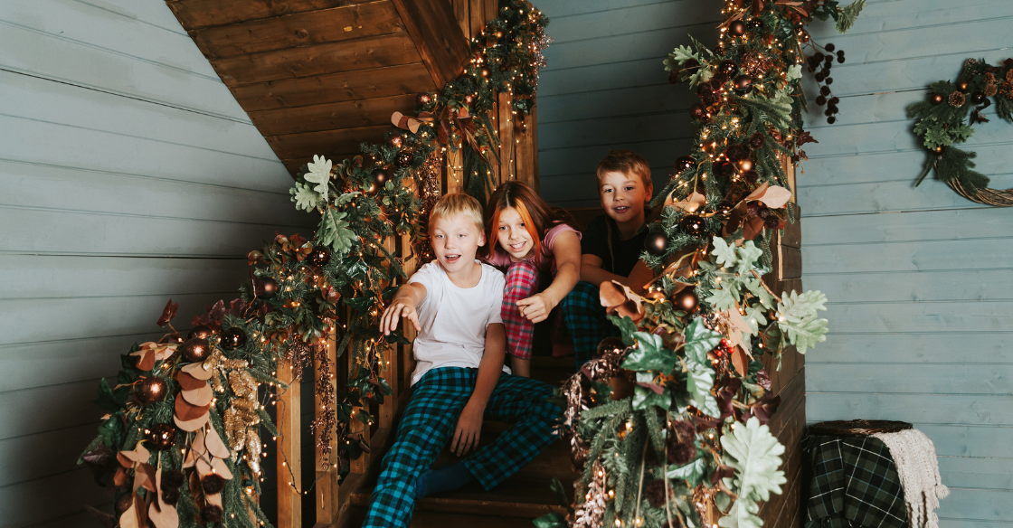 Happy children sitting on a staircase decorated with a Christmas garland